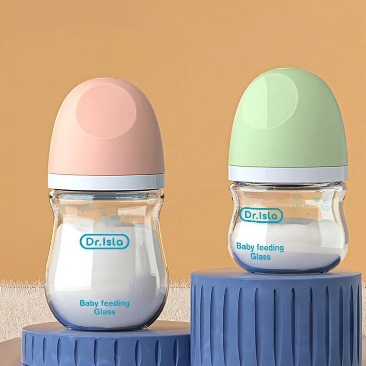 Two baby feeding bottles with pastel-colored caps; one bottle has a pink cap, and the other has a light green cap. Both bottles are labeled 'Dr. Isla Baby feeding Glass'.