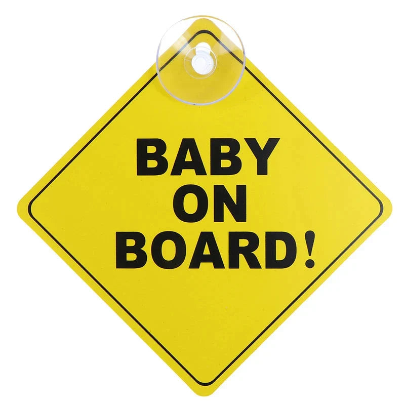 A simple yellow diamond-shaped sign with the text "BABY ON BOARD!" attached with a suction cup.