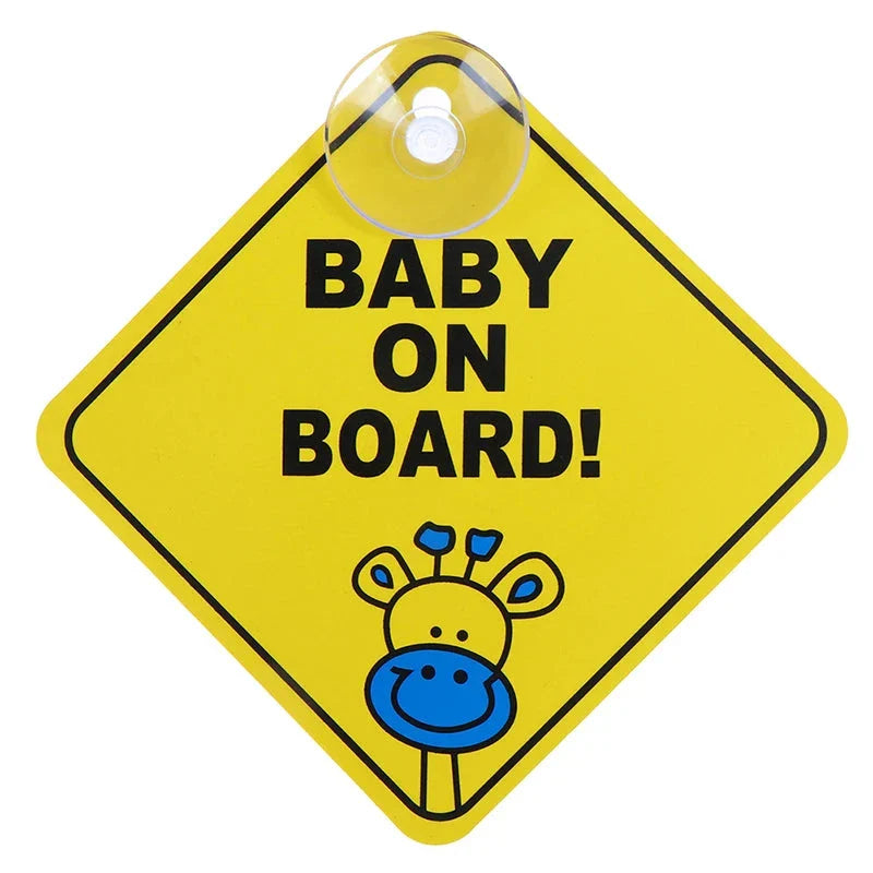 A yellow diamond-shaped sign with a giraffe illustration and the text "BABY ON BOARD!" attached with a suction cup.