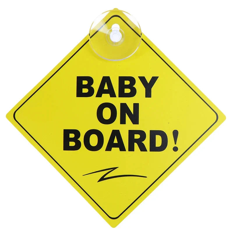 A yellow diamond-shaped sign with a swirl illustration and the text "BABY ON BOARD!" attached with a suction cup.