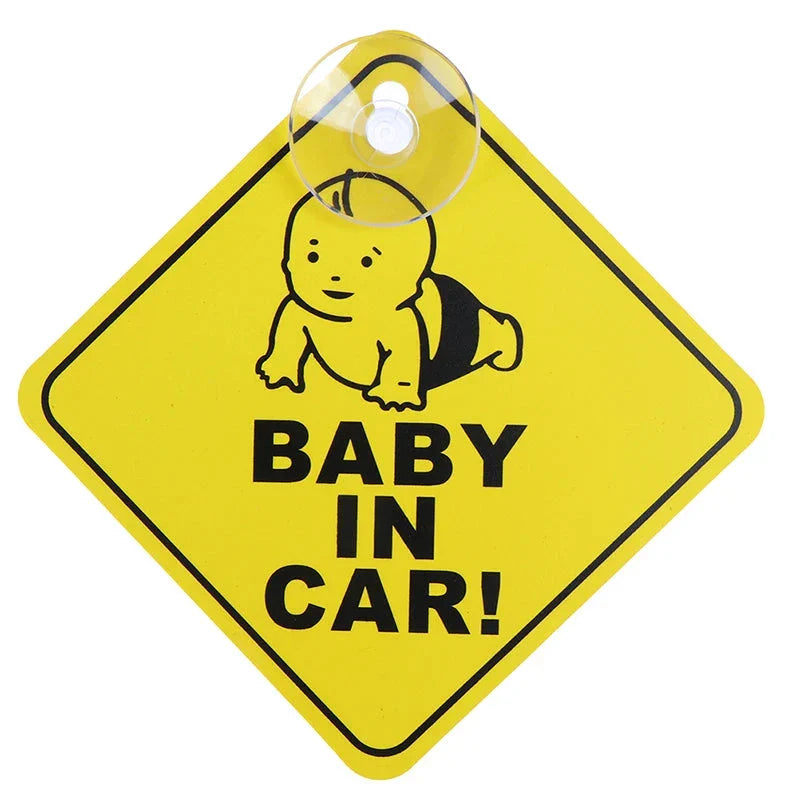 A yellow diamond-shaped sign featuring a crawling baby illustration and the text "BABY IN CAR!" attached with a suction cup.