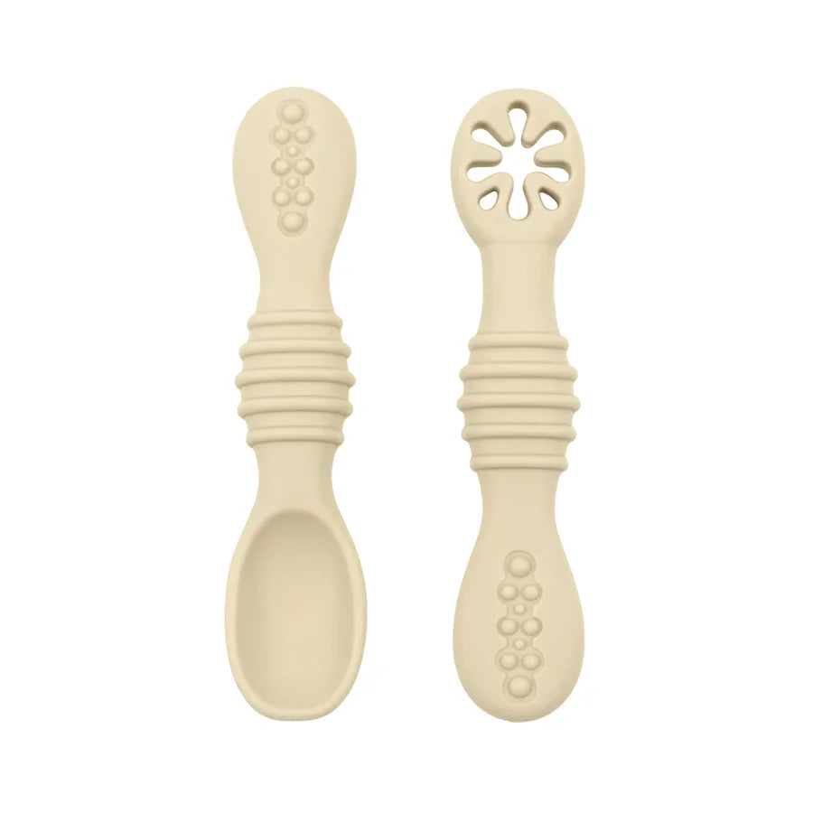 A close-up of two beige baby spoons, one with a regular spoon shape and the other with a cut-out flower design, against a white background.