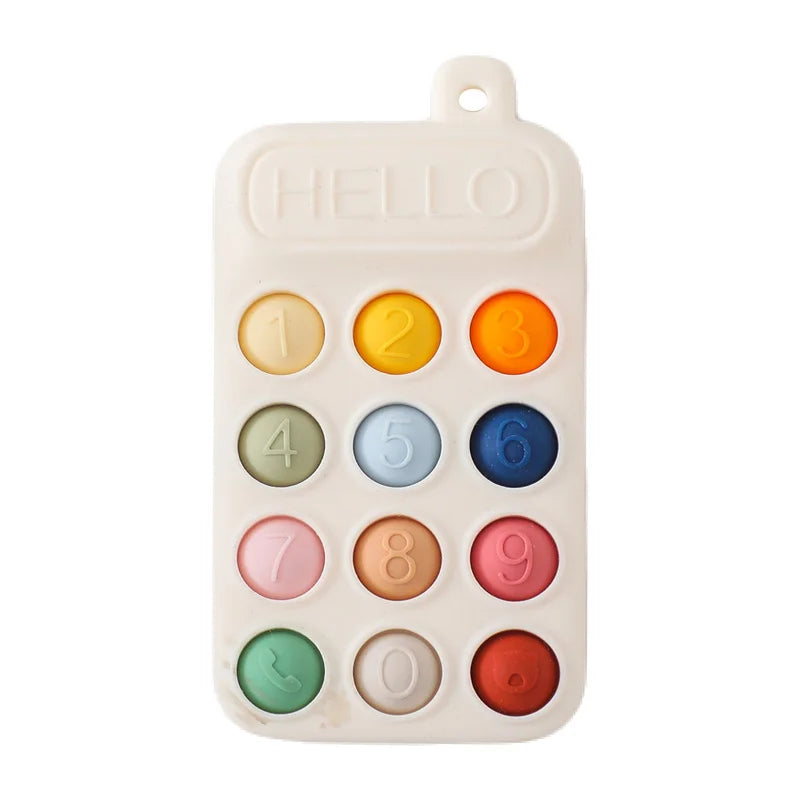 A cream silicone teether resembling a phone keypad with colorful buttons and the word "HELLO" at the top.